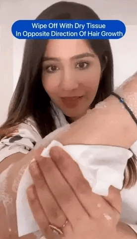 Hair spray foam on a person’s arm as they wipe it off with tissue.