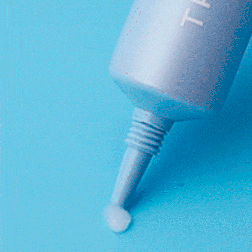 Eye cream applicator nozzle dispensing a white cream drop