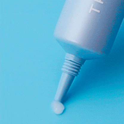 Eye cream applicator nozzle dispensing a white cream drop