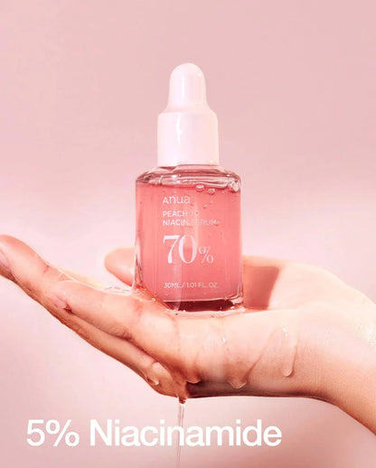 Anua 70% Peach Niacin Serum bottle in hand, pink dropper vial