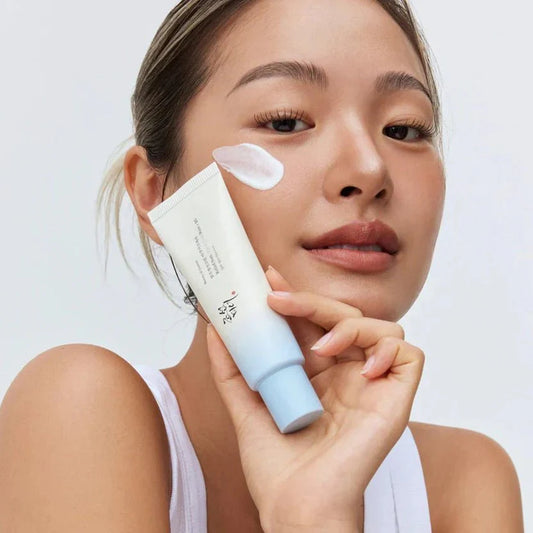 Sunscreen tube applying white cream to a woman’s cheek