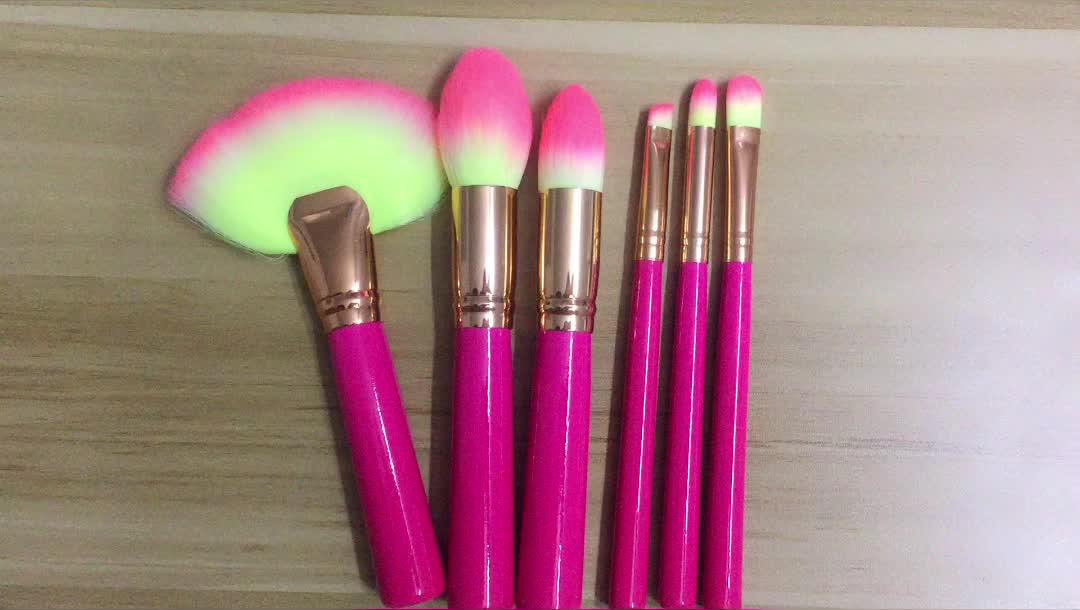 Makeup brush set with dark pink handles and gold ferrules, soft bristles fanned out
