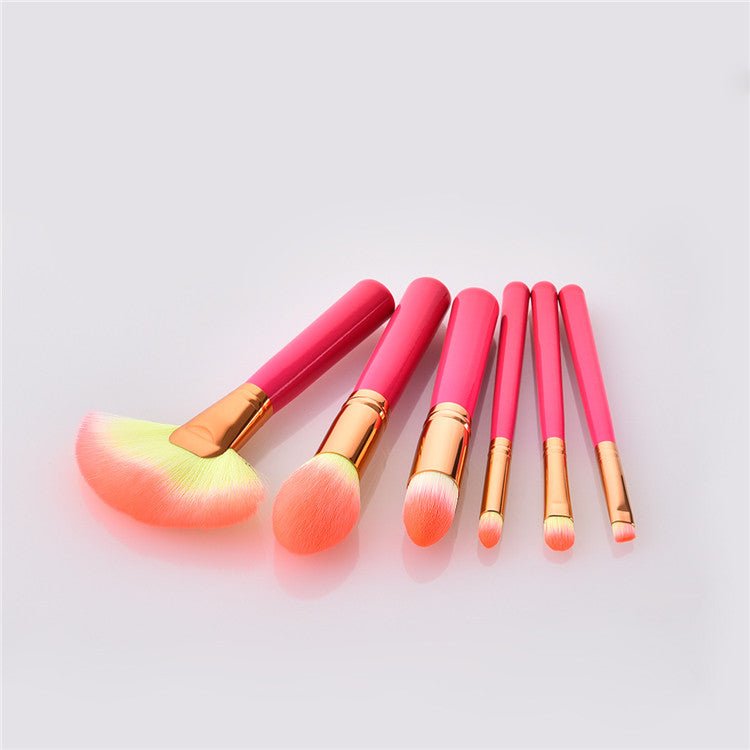 Makeup brush set with bright pink handles and gold ferrules, fan and small round brush heads
