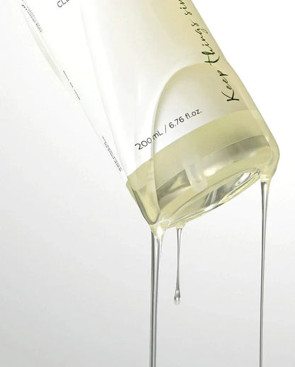 Close-up of pale yellow cleansing oil pouring from bottle spout