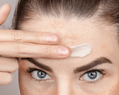 Skincare cream applied to forehead with fingers for smoothing dark spots