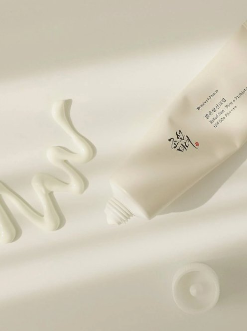 SPF50+ sunscreen cream tube close-up, light beige with printed logo