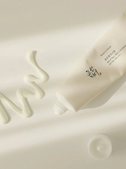 SPF50+ sunscreen cream tube close-up, light beige with printed logo
