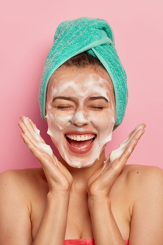 Foaming face cleanser applied with teal head towel