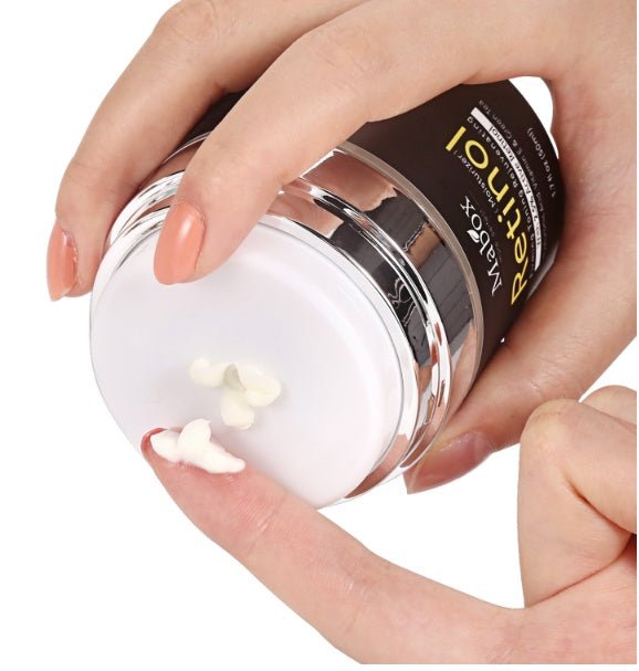 Open MaBox retinol eye cream jar held in hands with white cream dollops