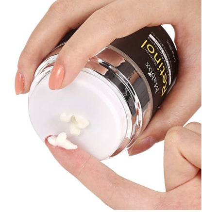 Open MaBox retinol eye cream jar held in hands with white cream dollops